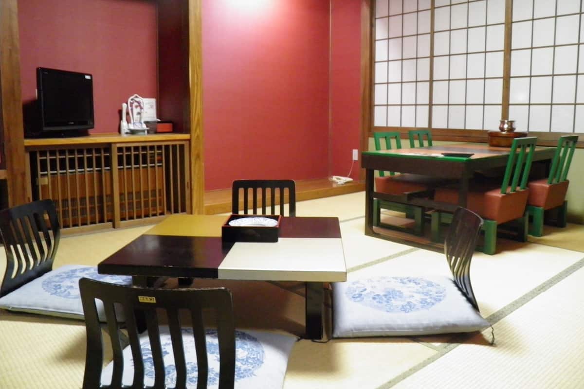 Um quarto japonês tradicional com tatames, uma mesa baixa e cadeiras verdes.