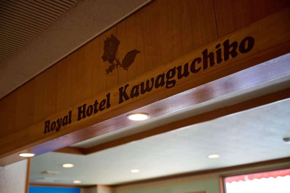 Een houten bord met de tekst 'Royal Hotel Kawaguchiko' en een silhouet van een vogel.