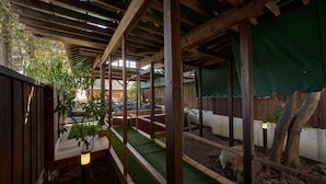 Eine Holzdielen-Terrasse mit Kunstgrasanlage, einem Blumentopf und einem Holzzaun.