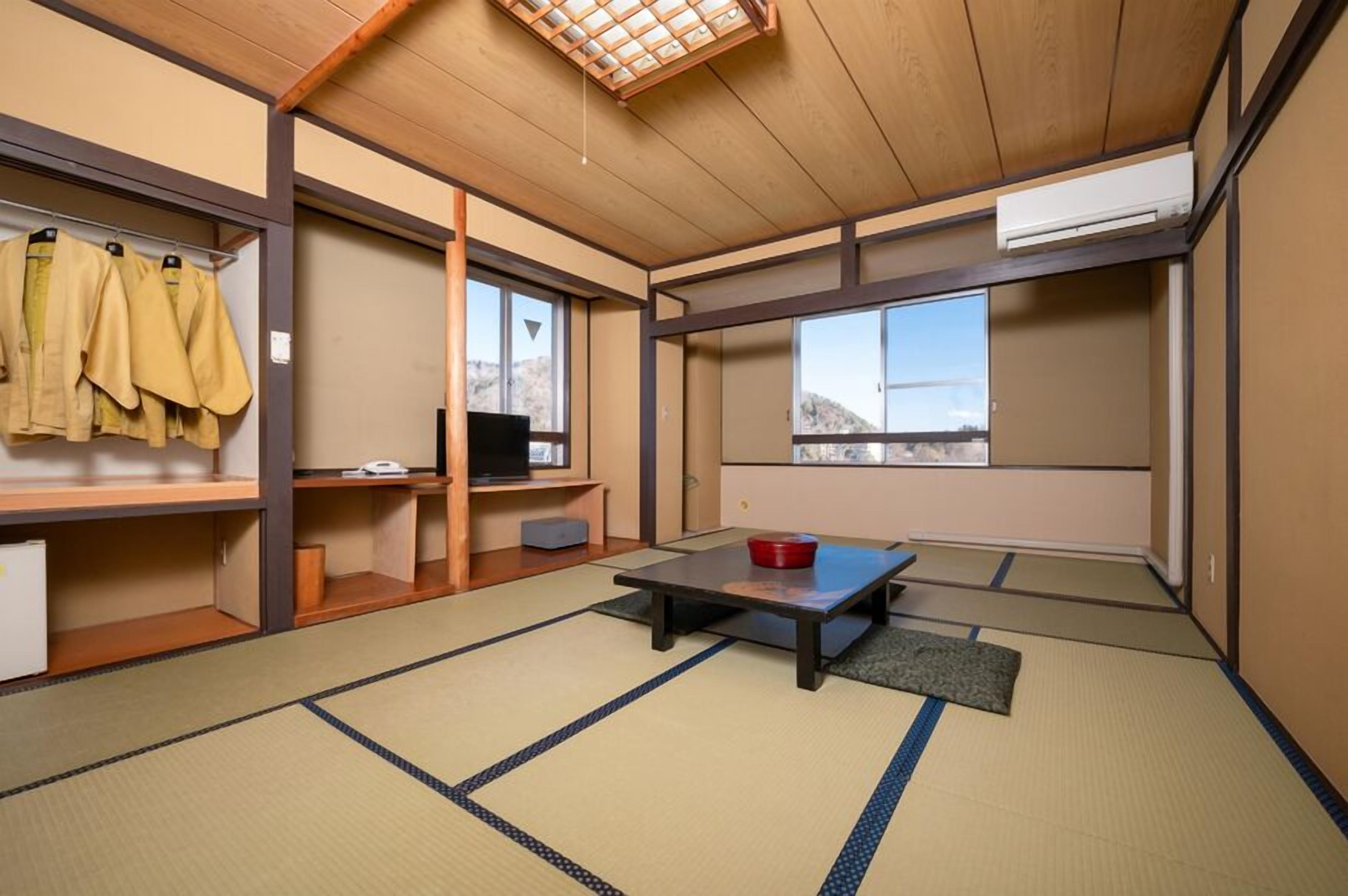 Een traditionele Japanse kamer met tatami vloerbedekking, een lage tafel en uitzicht op de omgeving.