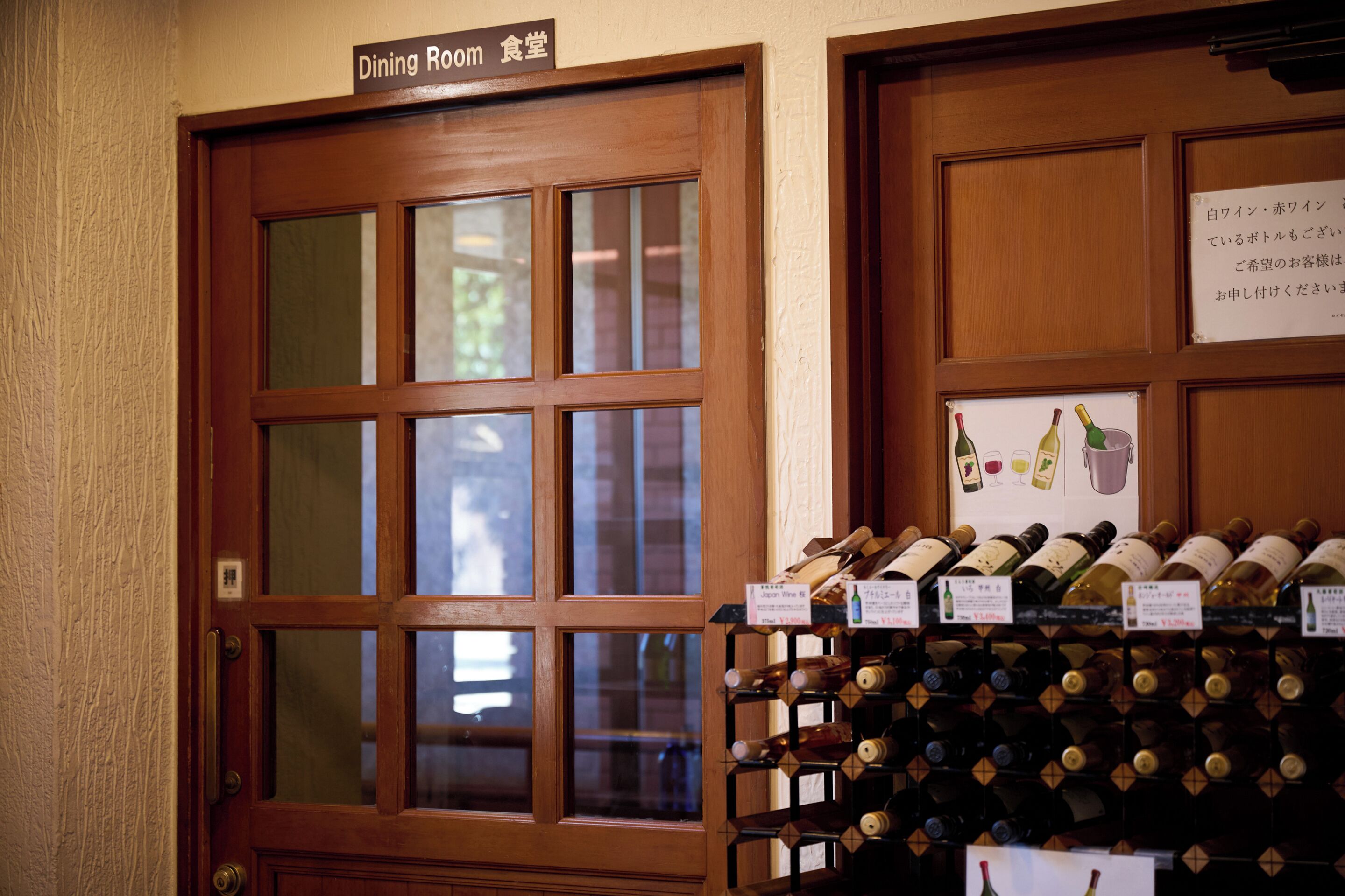 A wooden door labeled "Dining Room" with a wine rack filled with bottles.