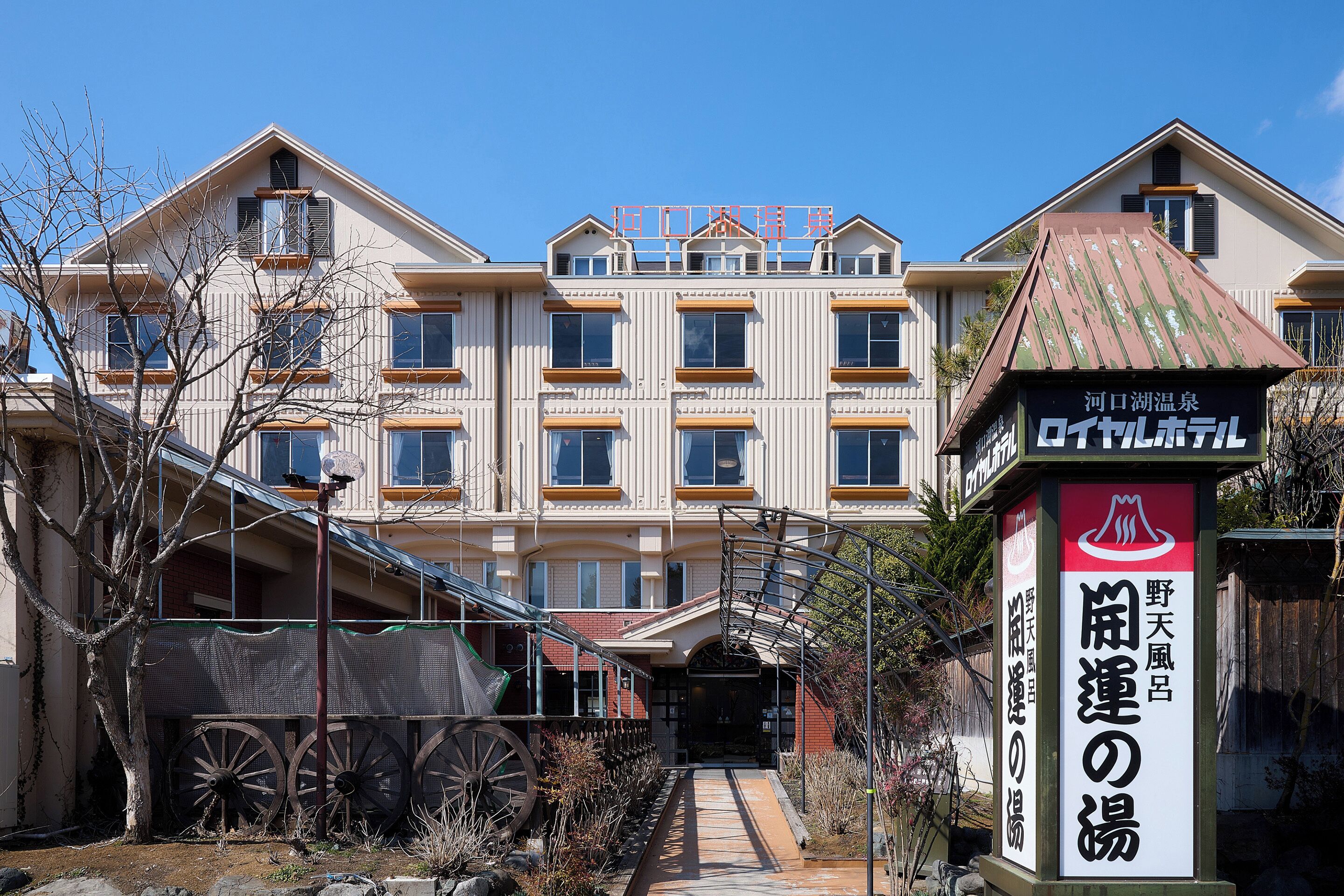 A multi-story hotel with a central entrance, a covered walkway, and a sign indicating a restaurant.