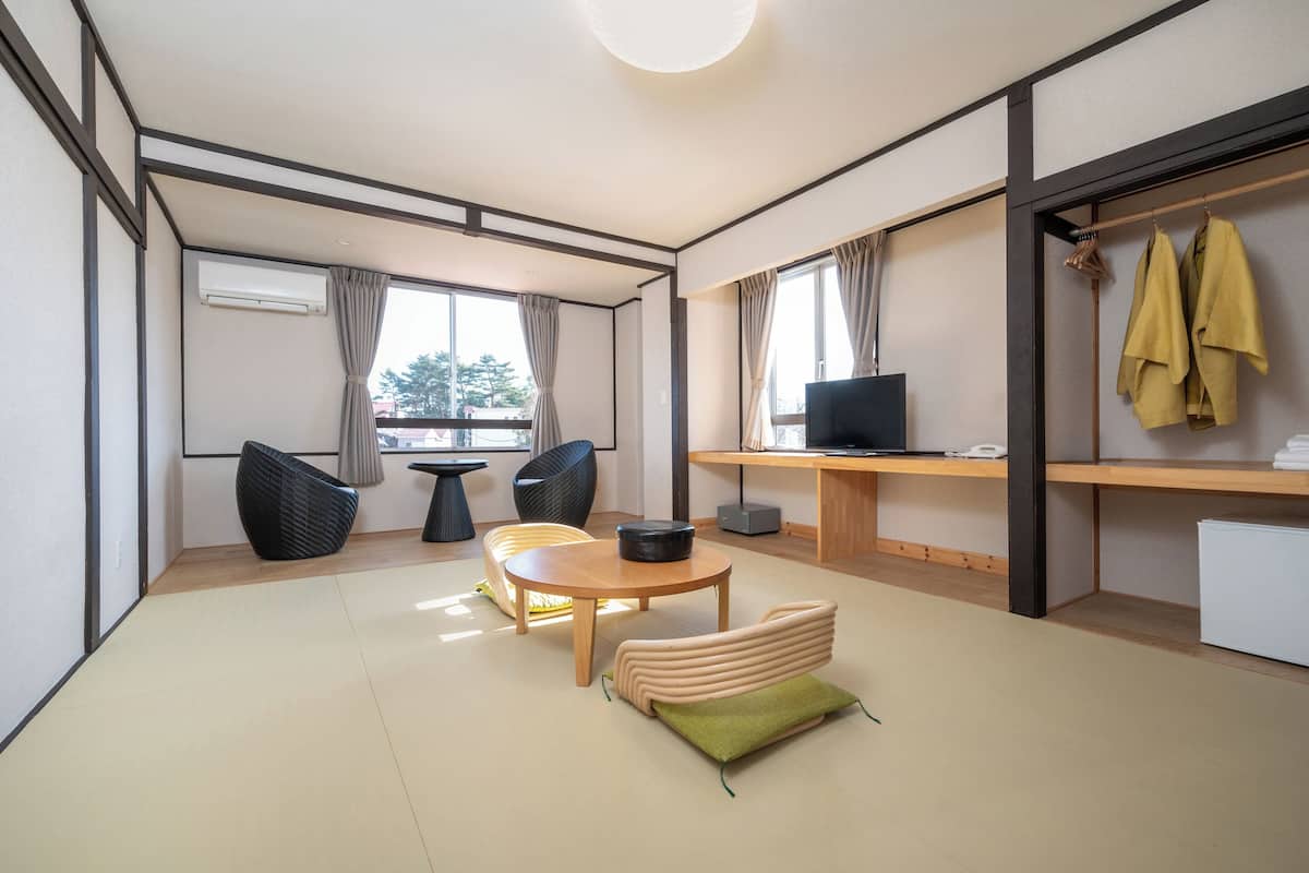 Een moderne woonkamer met een bank, stoelen, een bijzettafeltje, een televisie en een garderobe.