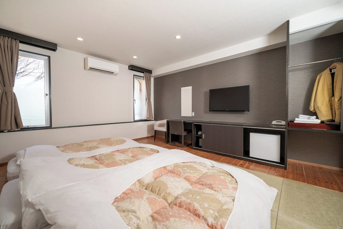 Een moderne hotelkamer met een groot bed, een bureau, een televisie en een kledingkast.
