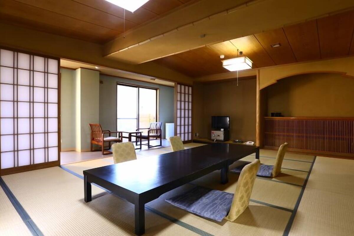 Une pièce de style japonais traditionnel, avec un sol recouvert de tatamis, une table basse et des portes coulissantes.
