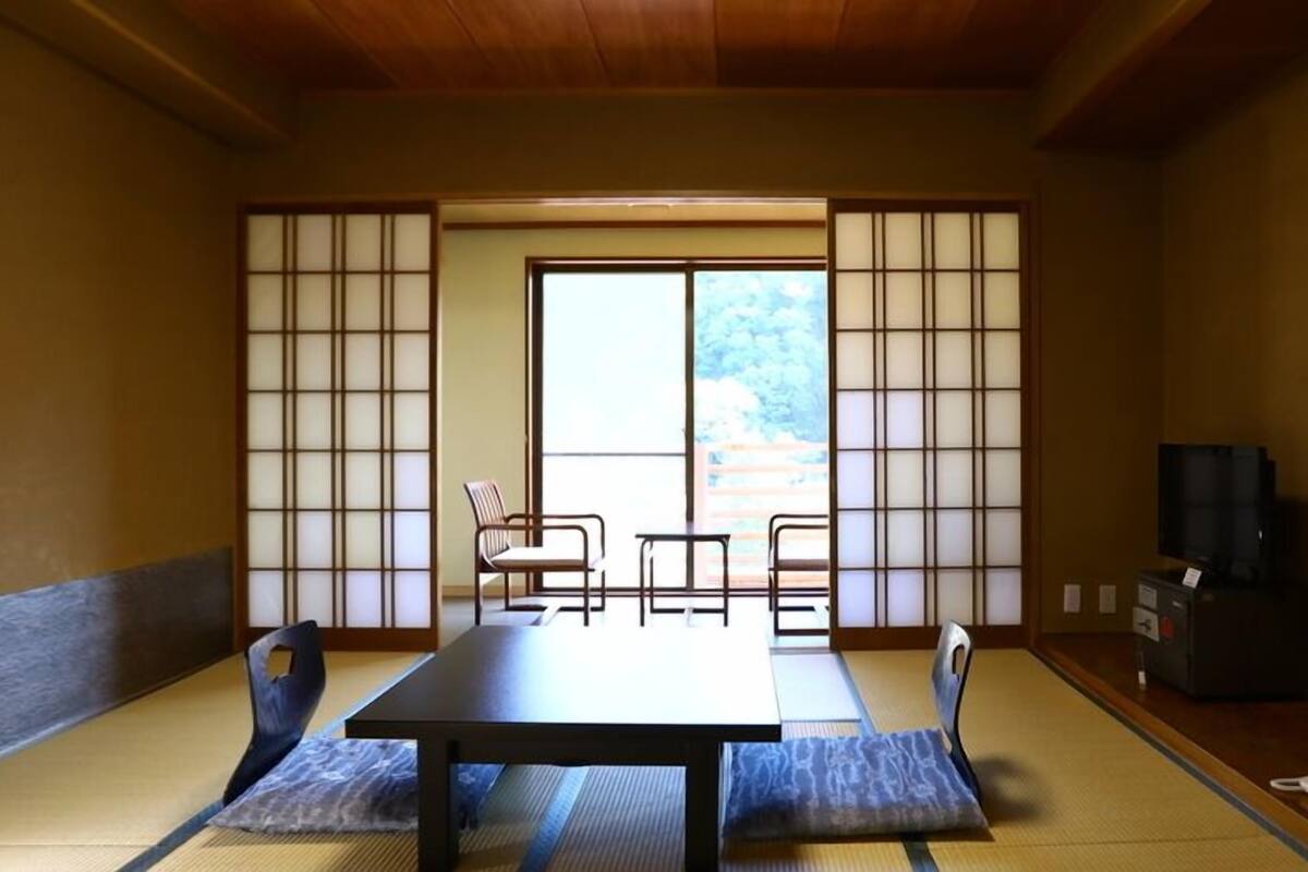 Une pièce de style japonais traditionnel, avec un sol recouvert de tatamis, une table basse et des portes coulissantes.