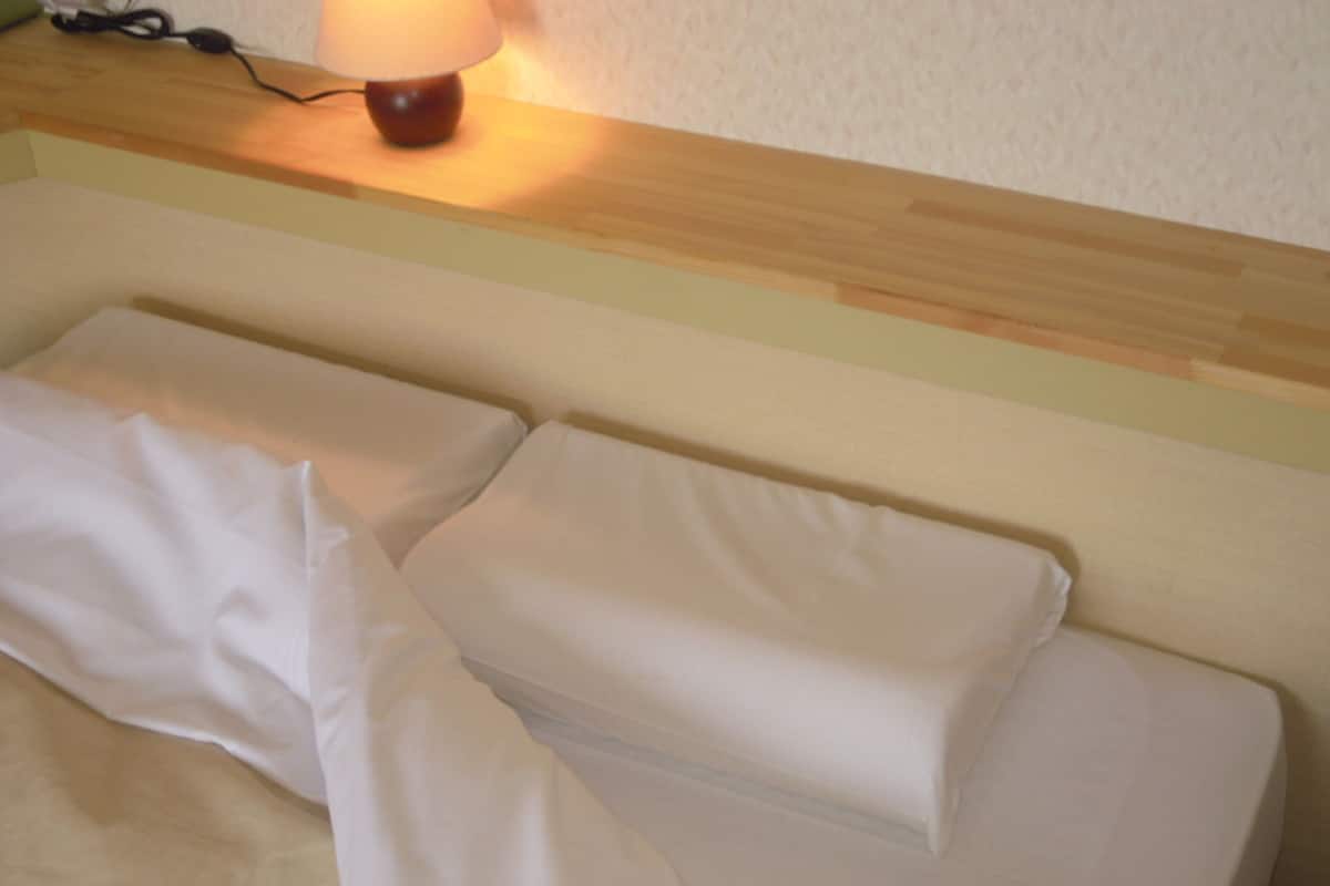Ein Bett mit weißer Bettwäsche und einem hölzernen Kopfteil.