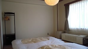 A bedroom with a bed, a radiator, a window with curtains, and a hanging light fixture. - Niigata Park Hotel (Niigata)