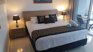 Habitación de hotel con una cama grande, dos lámparas de noche, un cuadro en la pared y vistas por la ventana.