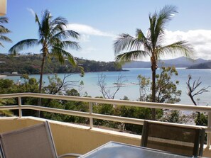 A balcony with a view of a beach and palm trees. - Frangipani 103 (Whitsundays)