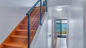A wooden staircase with a blue handrail leading to a door with a view of the sea. - Panorama 12 (Whitsundays)