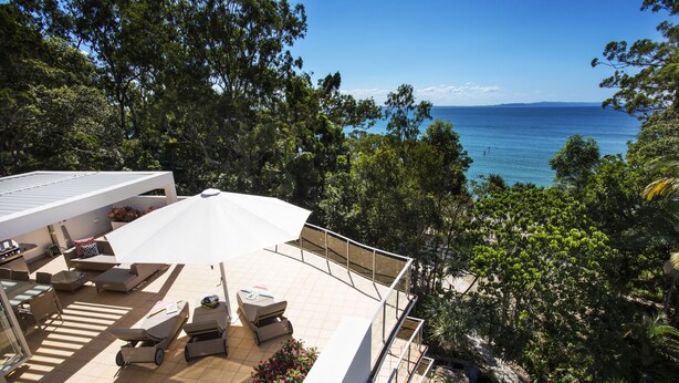 A rooftop terrace with outdoor seating, a view of the sea, and surrounding greenery. - The Cove Noosa (Noosa Heads)