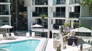 A modern hotel with a swimming pool, outdoor seating, and a multi-story building with balconies. - The Cove Noosa (Noosa Heads)