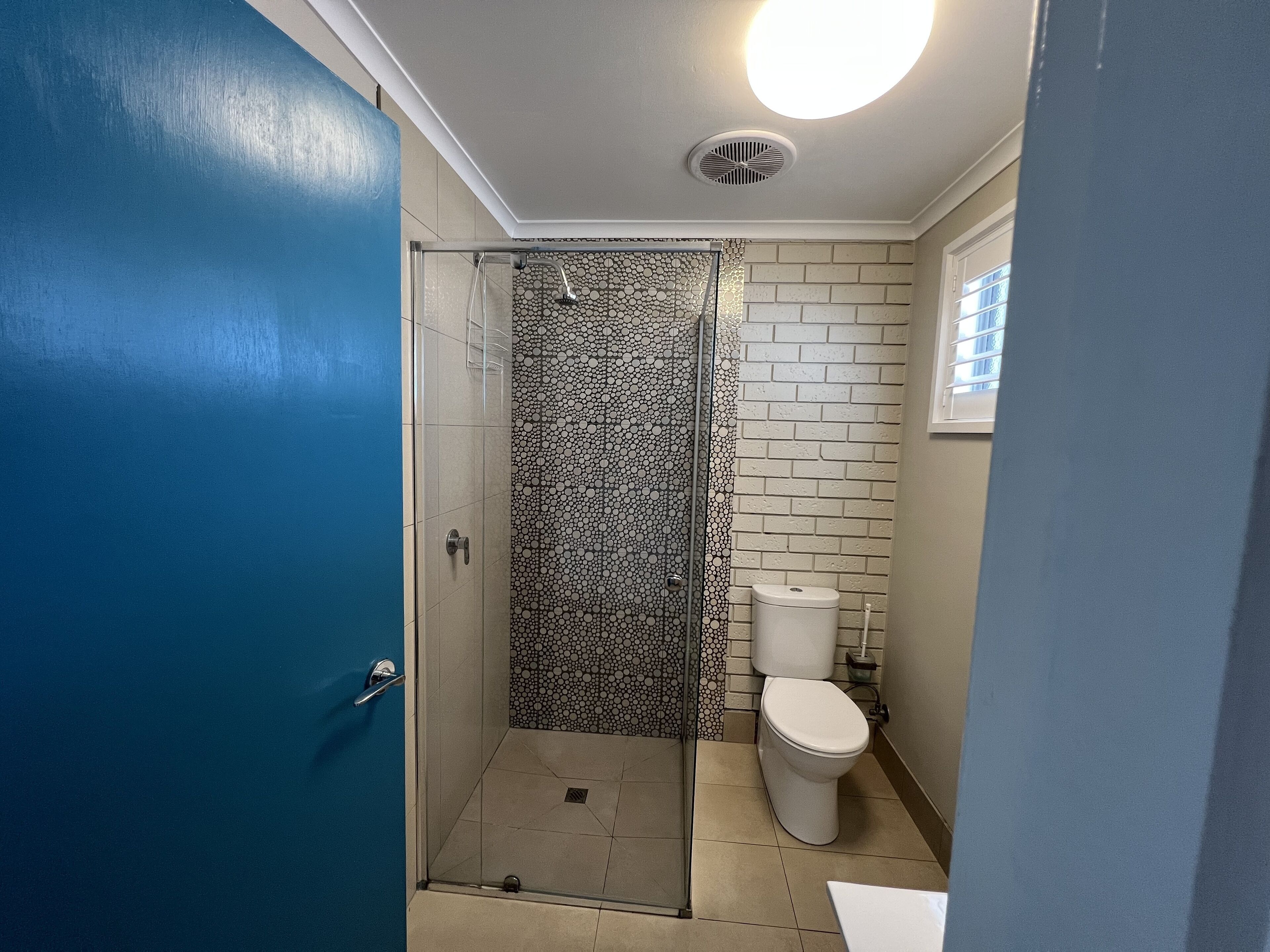 Un baño con ducha, inodoro y una puerta azul.