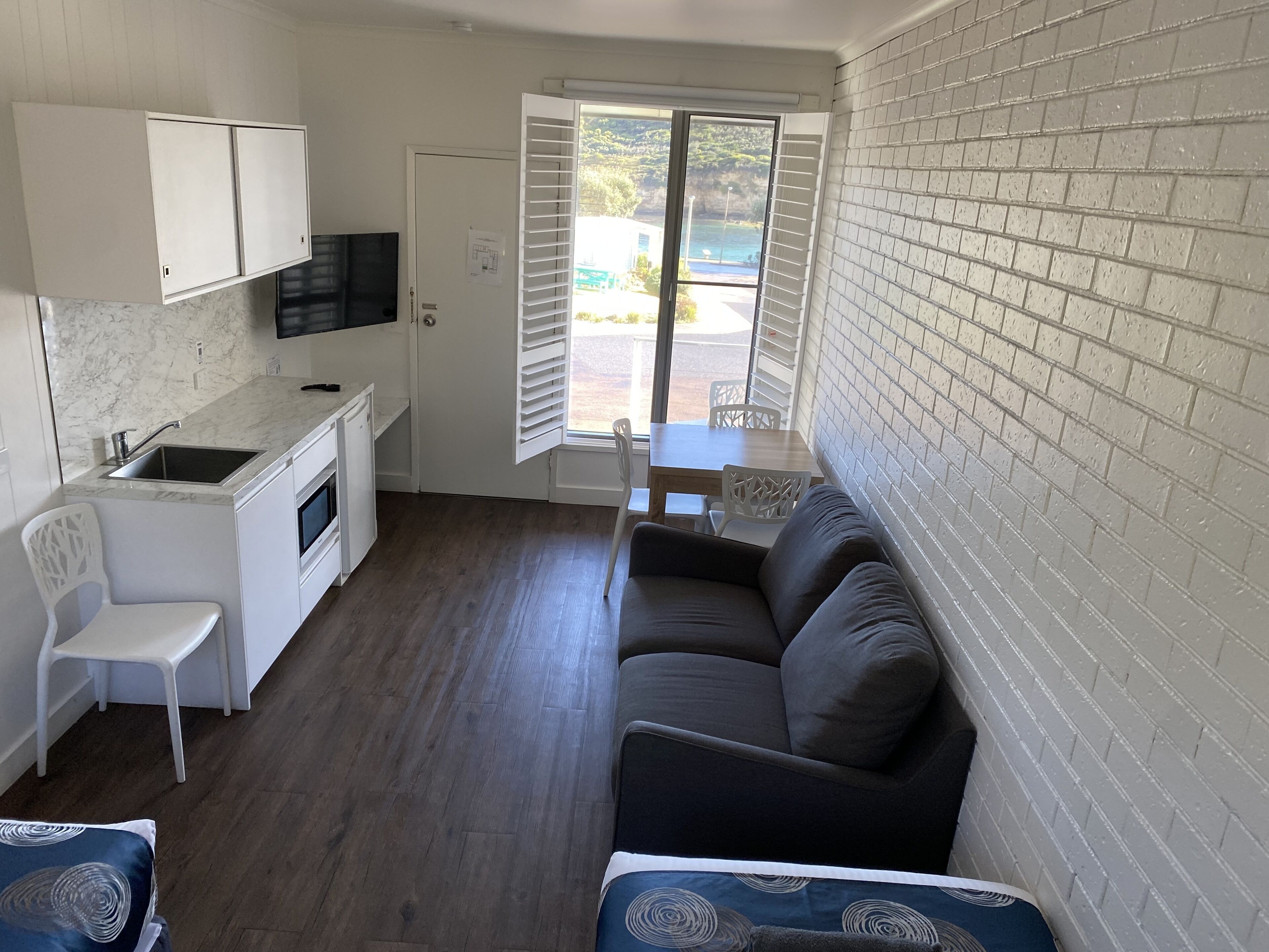 A compact living space with a kitchenette, a sofa, a dining table, and a view of the outdoors.