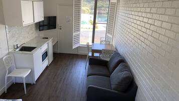 A compact living space with a kitchenette, a sofa, a dining table, and a view of the outdoors.