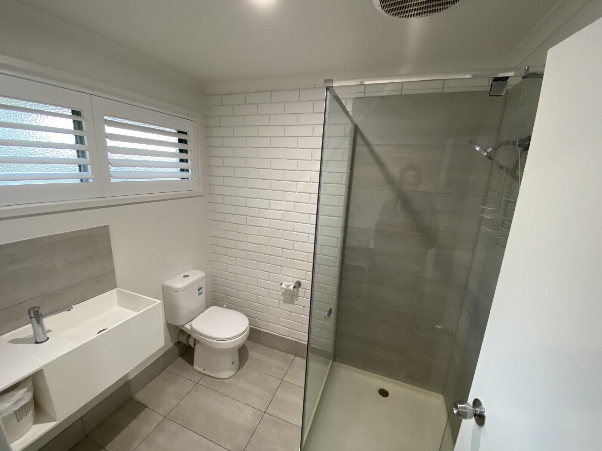 A modern bathroom with a glass-enclosed shower, a white toilet, and a large bathtub.