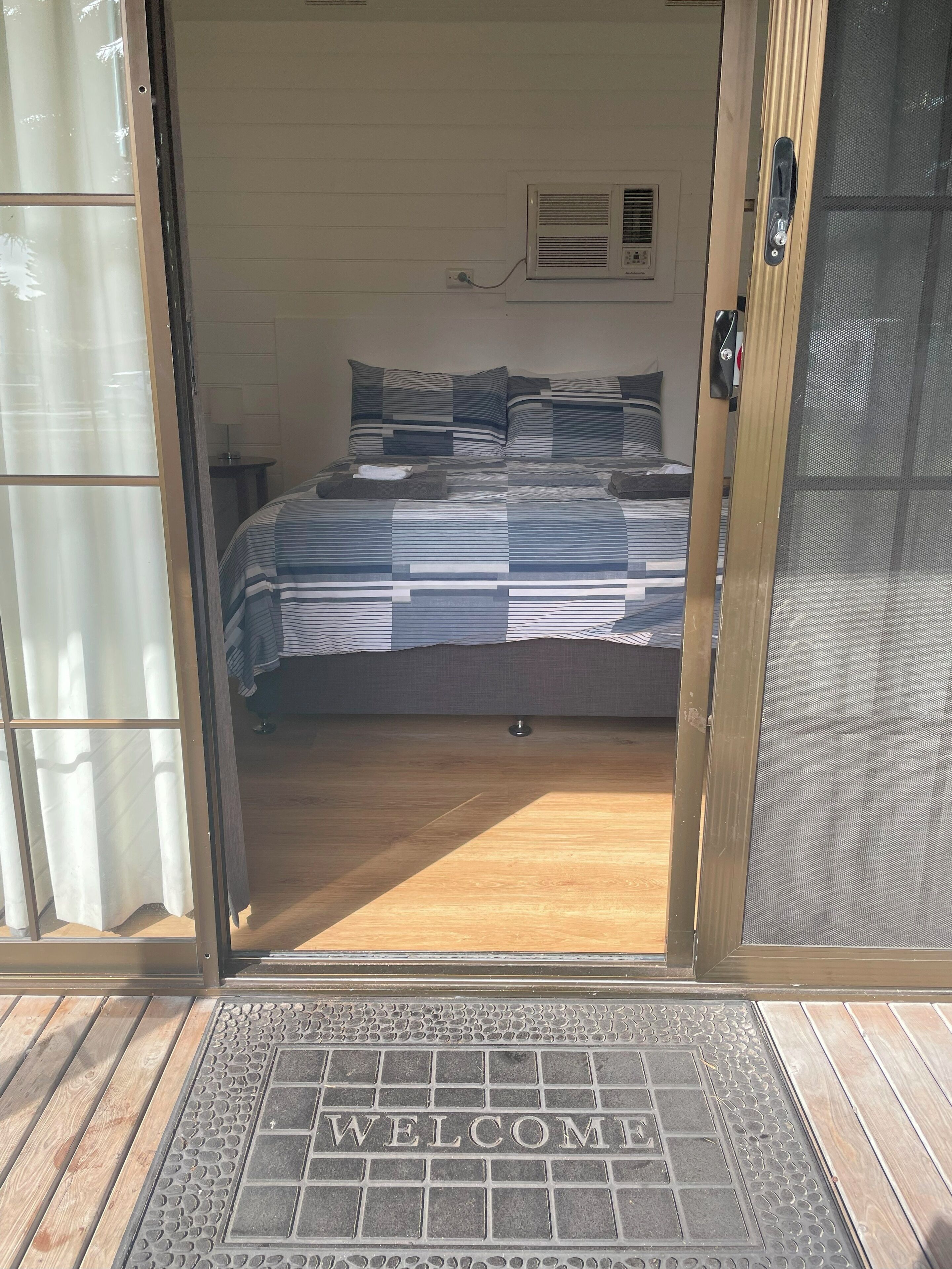 A bedroom with a bed, a bedside table, and a wall-mounted air conditioner.