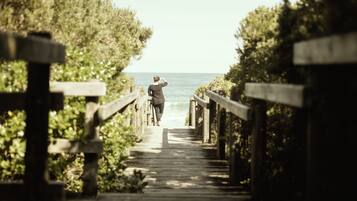 A wooden boardwalk leading to a beach with a person walking.