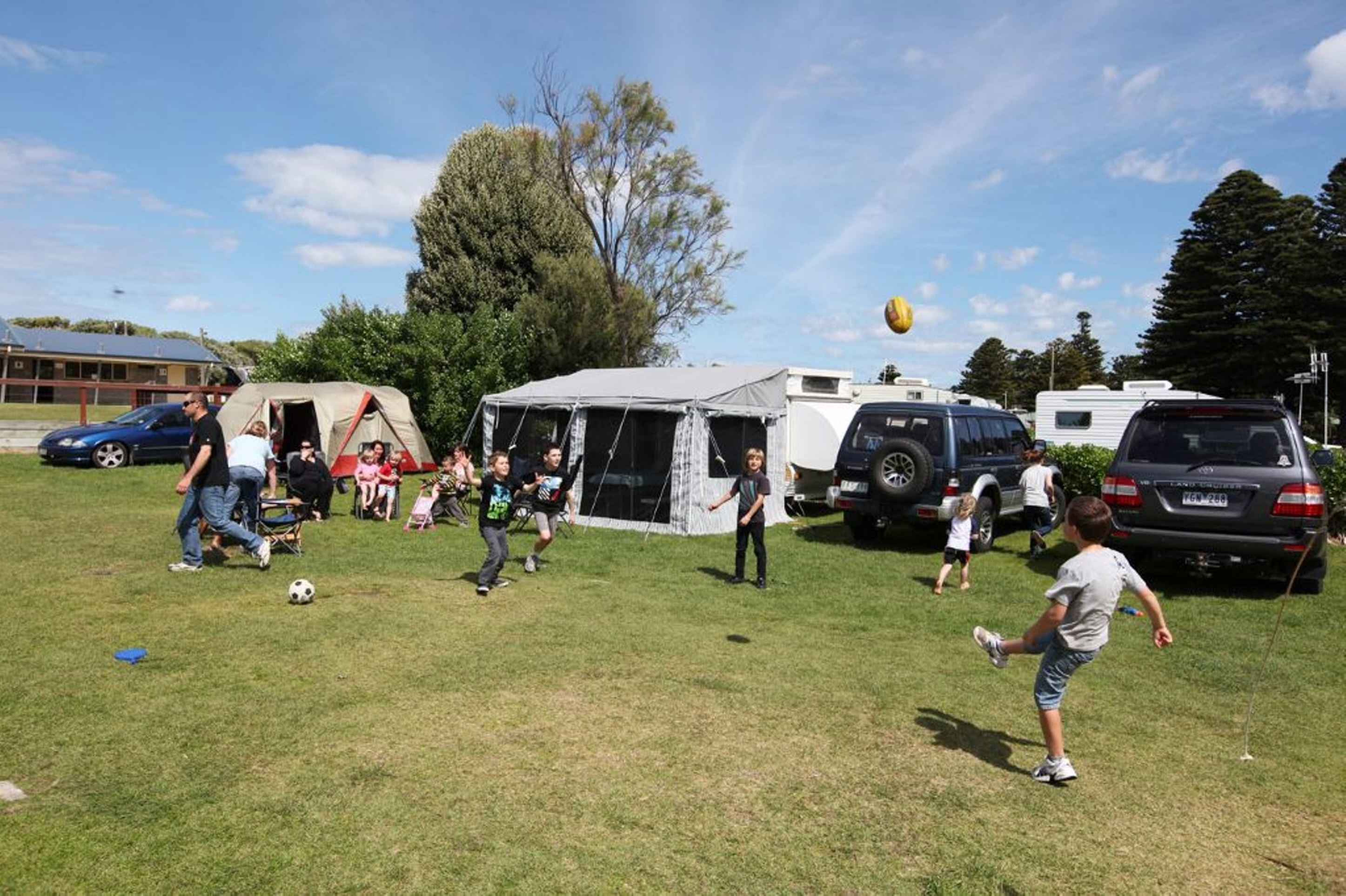 Un campo cubierto de césped con tiendas de campaña y vehículos recreativos, lo que sugiere un entorno de camping o un evento al aire libre.