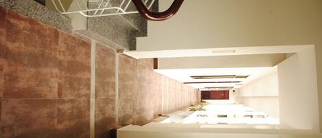 A modern interior with a staircase, a long corridor, and a view through a window.