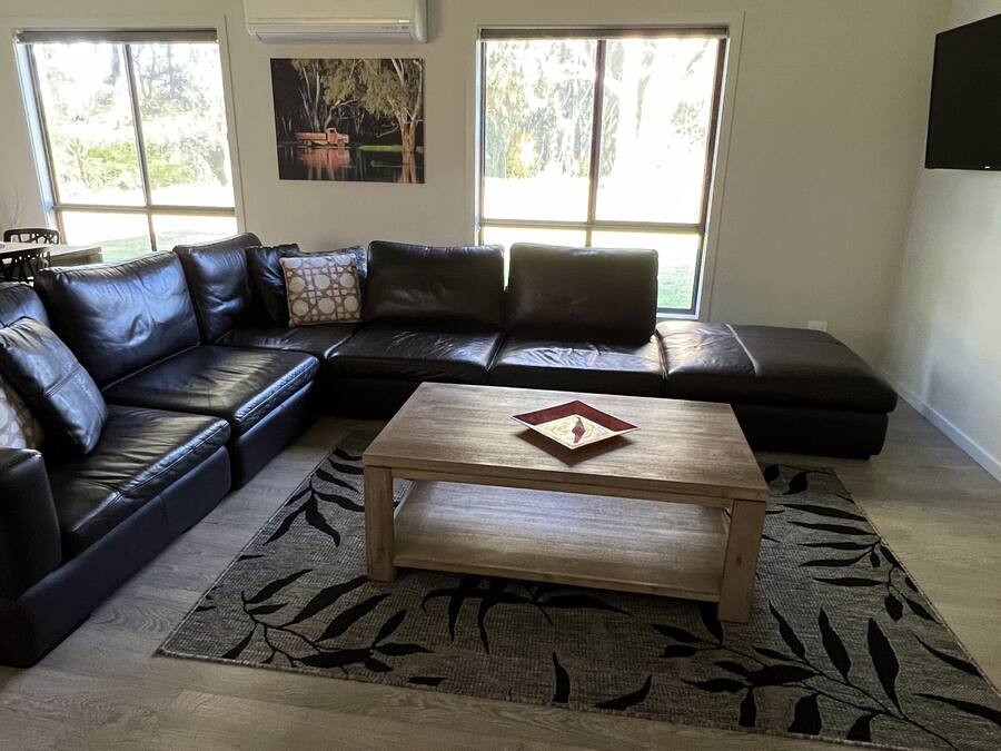Ein Wohnzimmer mit einer Eckcouch, einem Couchtisch und einem Teppich.