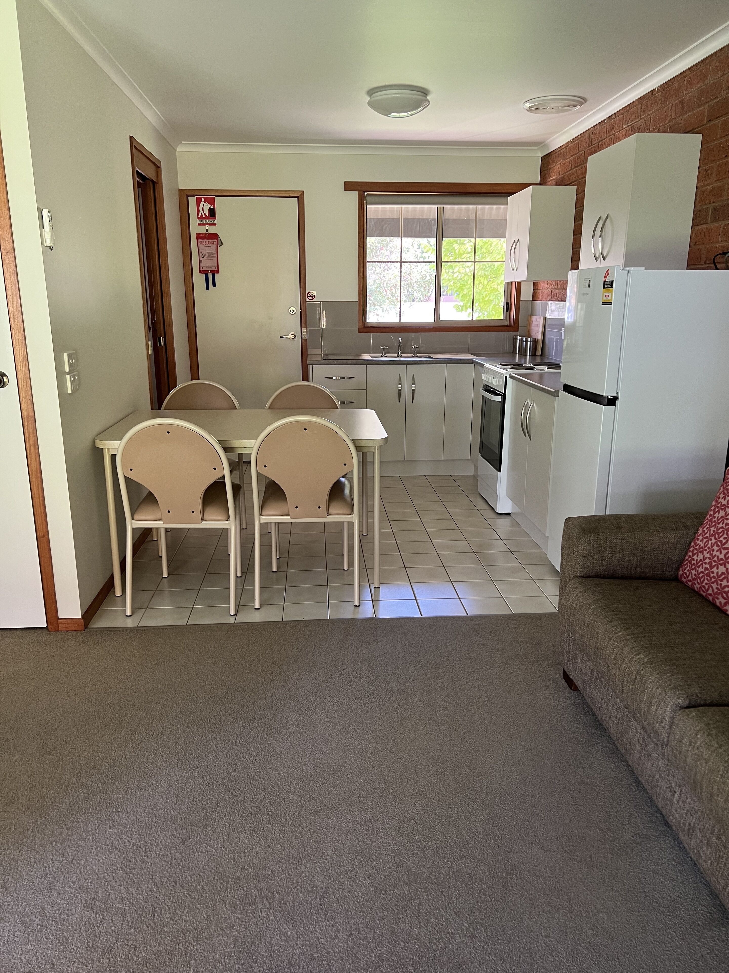 A compact kitchen with a dining area, a refrigerator, and a sofa.