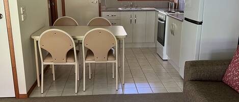 A compact kitchen with a dining area, a refrigerator, and a sofa.
