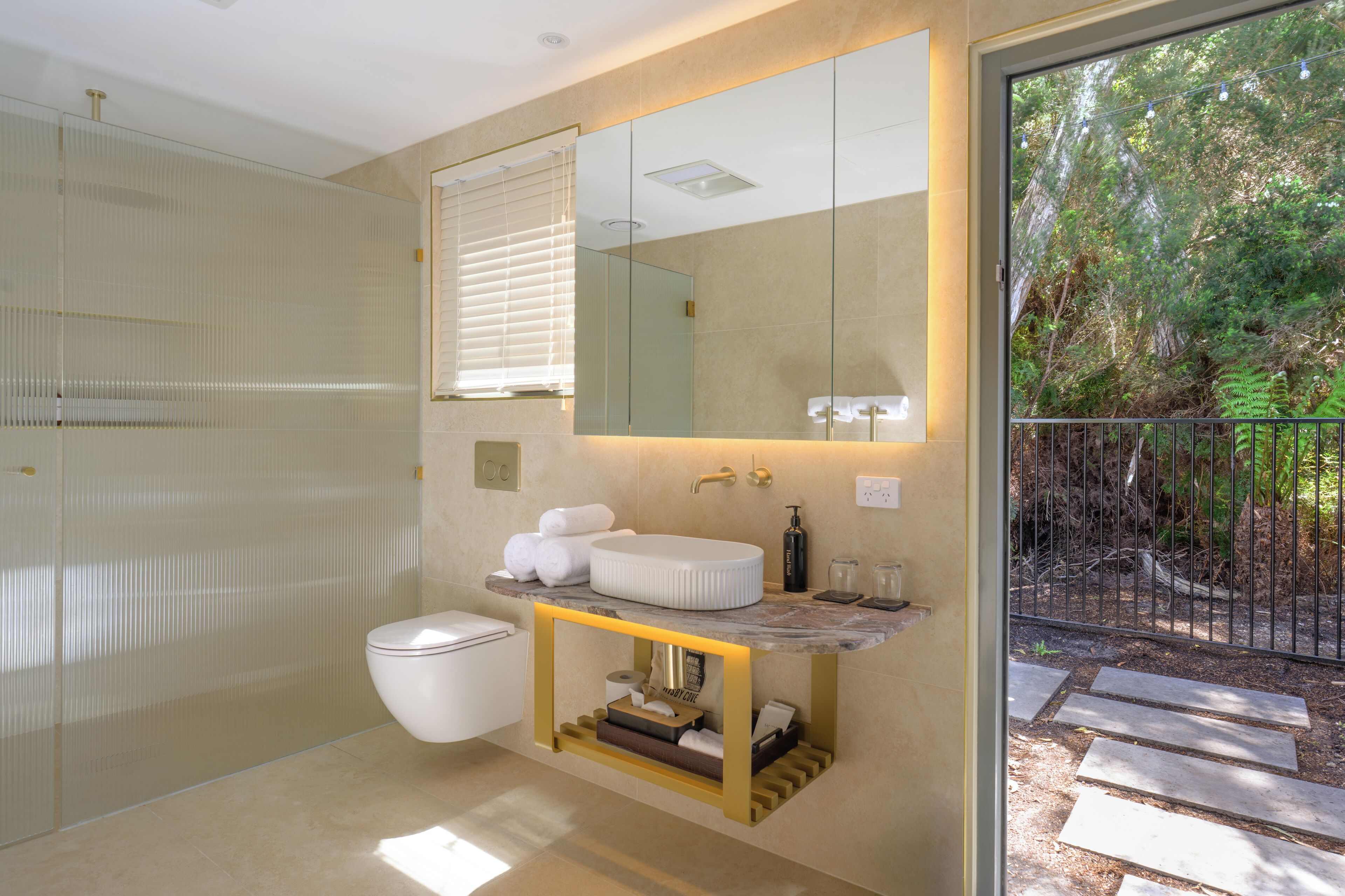 A modern bathroom with a glass shower enclosure, a marble sink, and a large mirror.