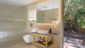 A modern bathroom with a glass shower enclosure, a marble sink, and a large mirror.