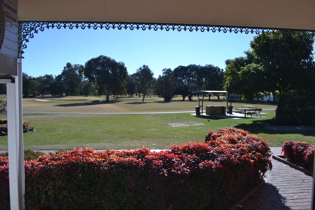 A view of a golf course with a pavilion and a picnic table.