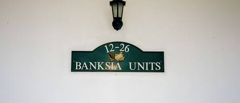 A sign with the text "12-26 BANKSIYA UNITS" and a decorative lamp above it.