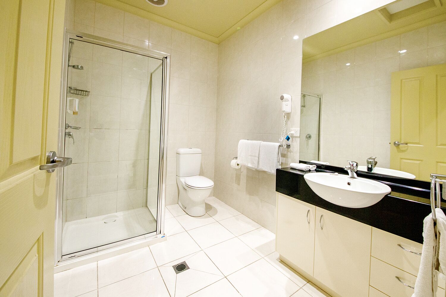 Un baño moderno con ducha de vidrio, inodoro blanco y lavabo con encimera negra.