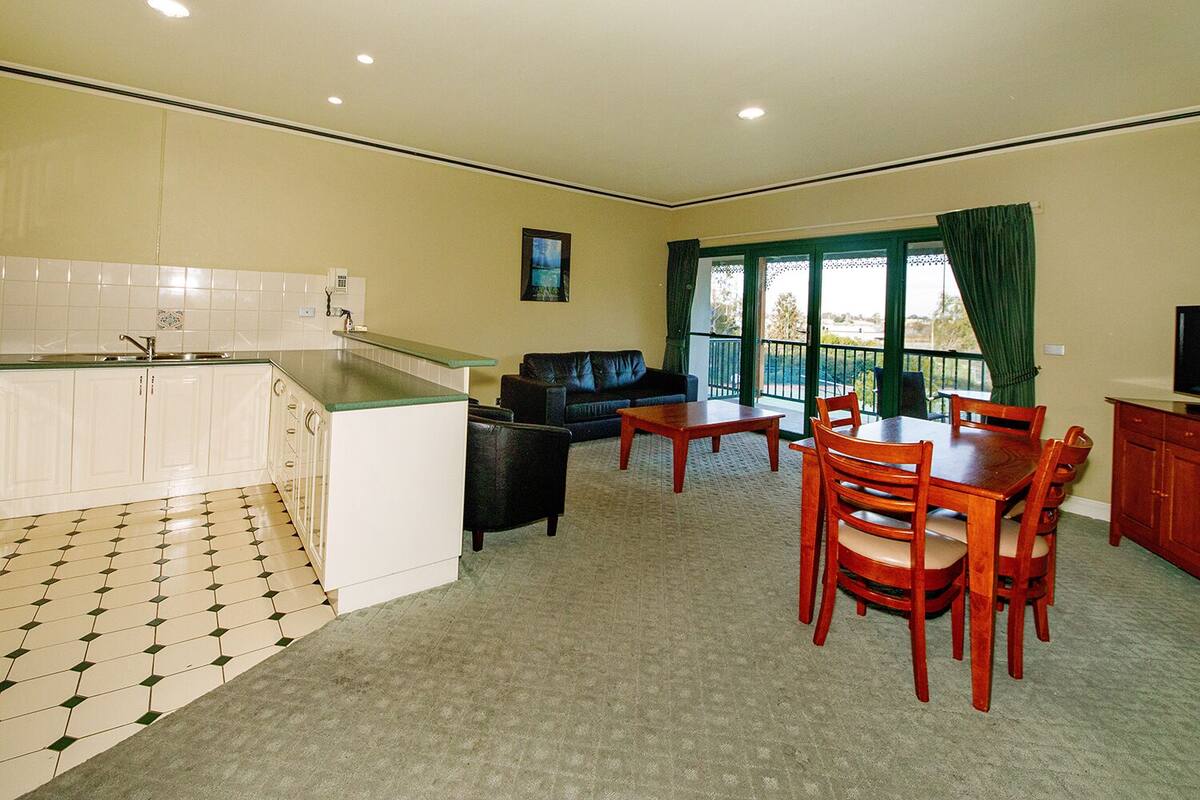 A compact living space with a kitchenette, dining area, and a balcony with a view.