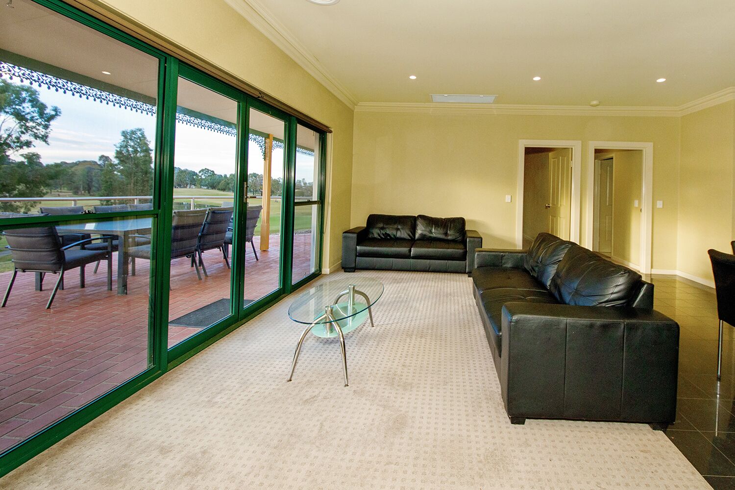 A spacious living room with a large glass door leading to an outdoor patio area.