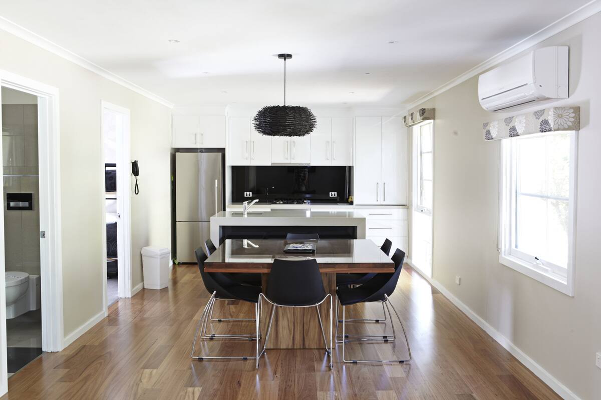 A modern kitchen with white cabinets, a central island, and a hanging light fixture.