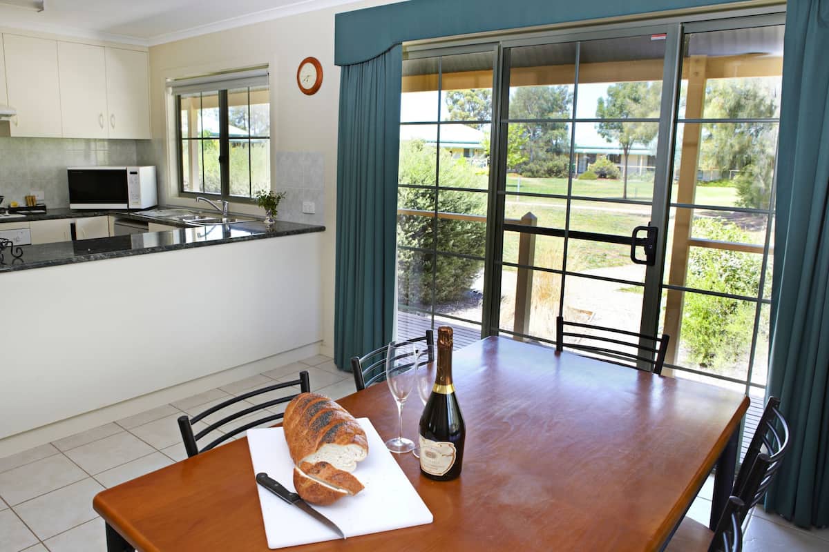A kitchen with a dining table, a loaf of bread, a bottle of wine, and a knife.