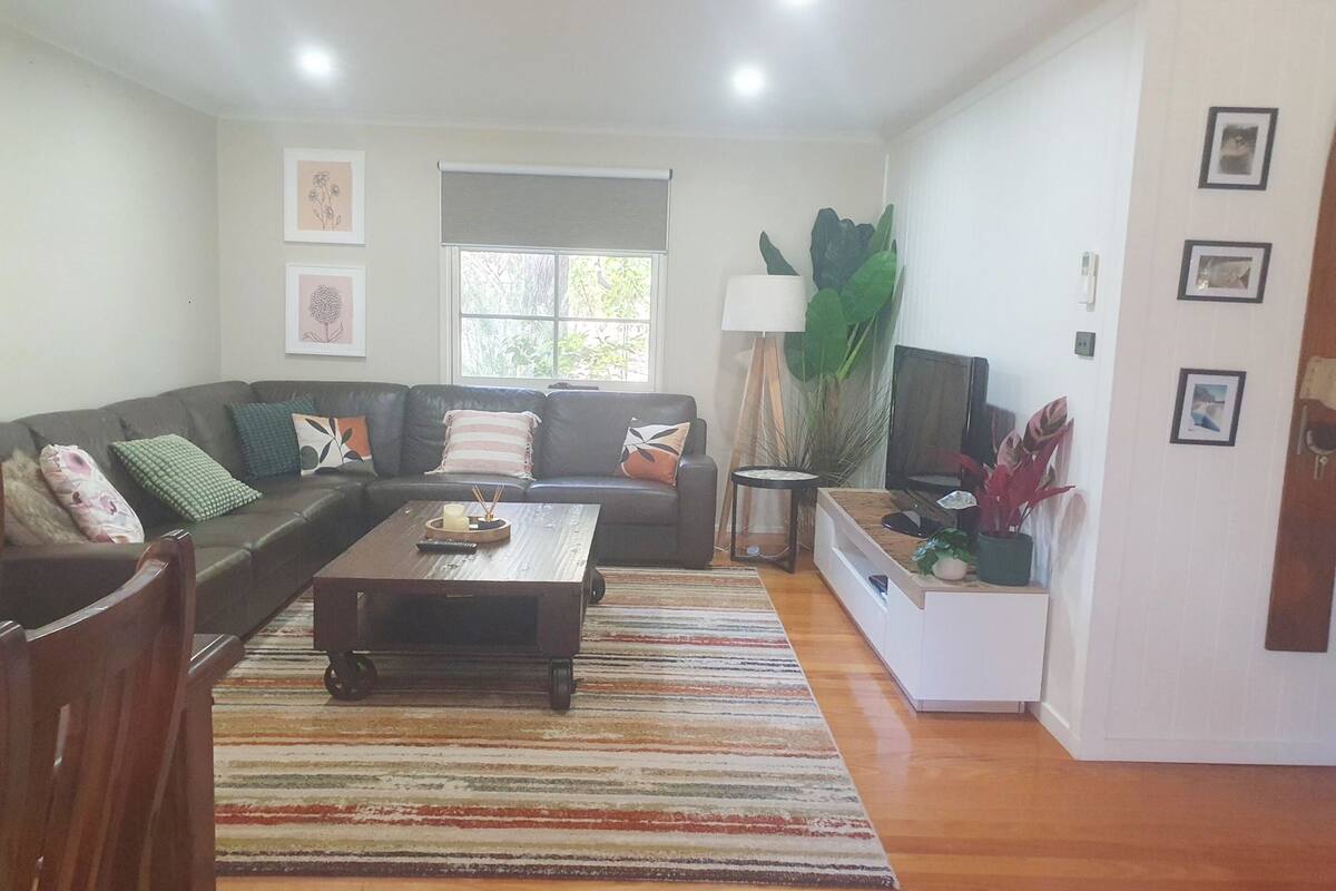 A living room with a sofa, coffee table, TV, and plants.