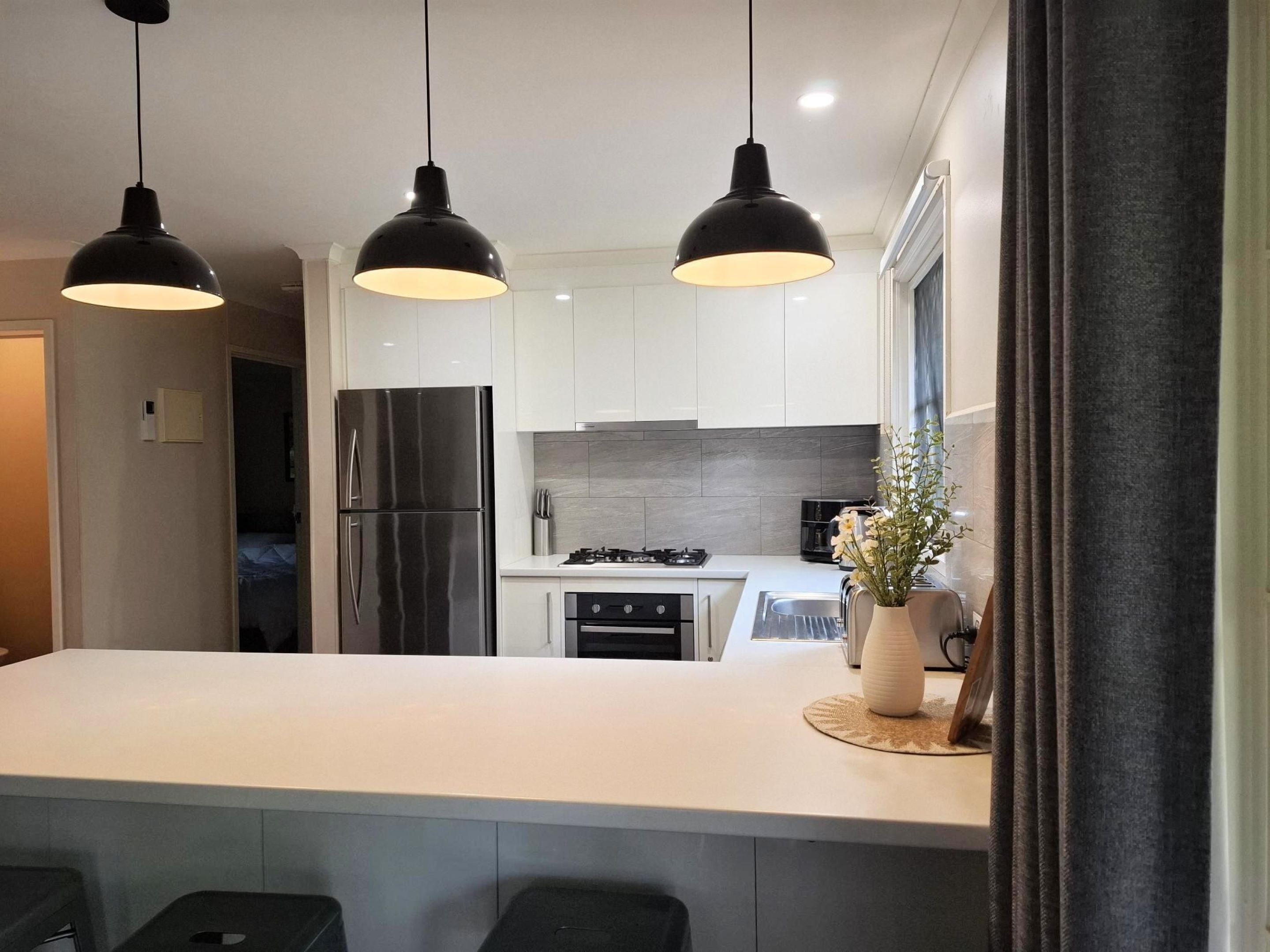 A modern kitchen with a central island, stainless steel appliances, and pendant lighting.
