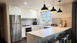 Una cocina moderna con electrodomésticos de acero inoxidable, una isla grande con taburetes de bar e iluminación colgante.