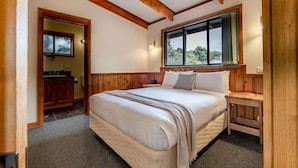 Une chambre à coucher avec un grand lit, une tête de lit en bois, une fenêtre donnant sur un beau paysage et une armoire en bois.