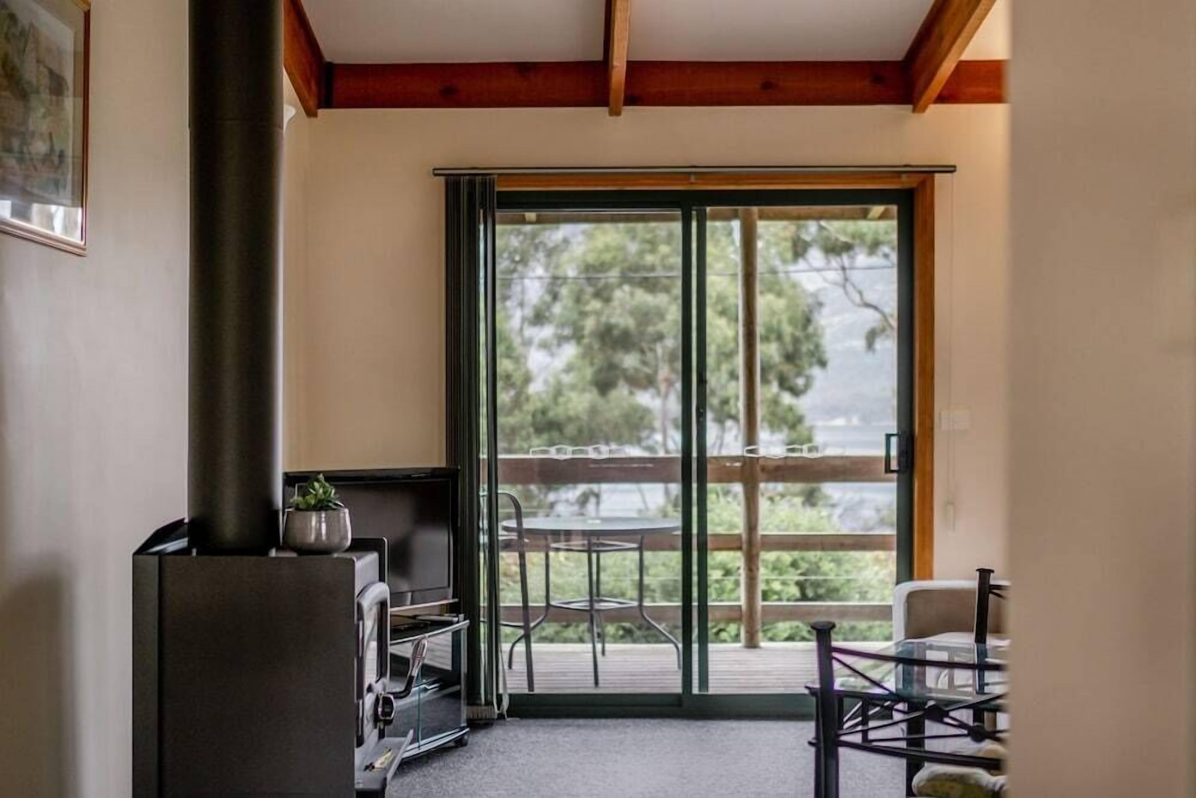 A room with a fireplace, a sliding glass door to an outdoor deck, and a small table with chairs.