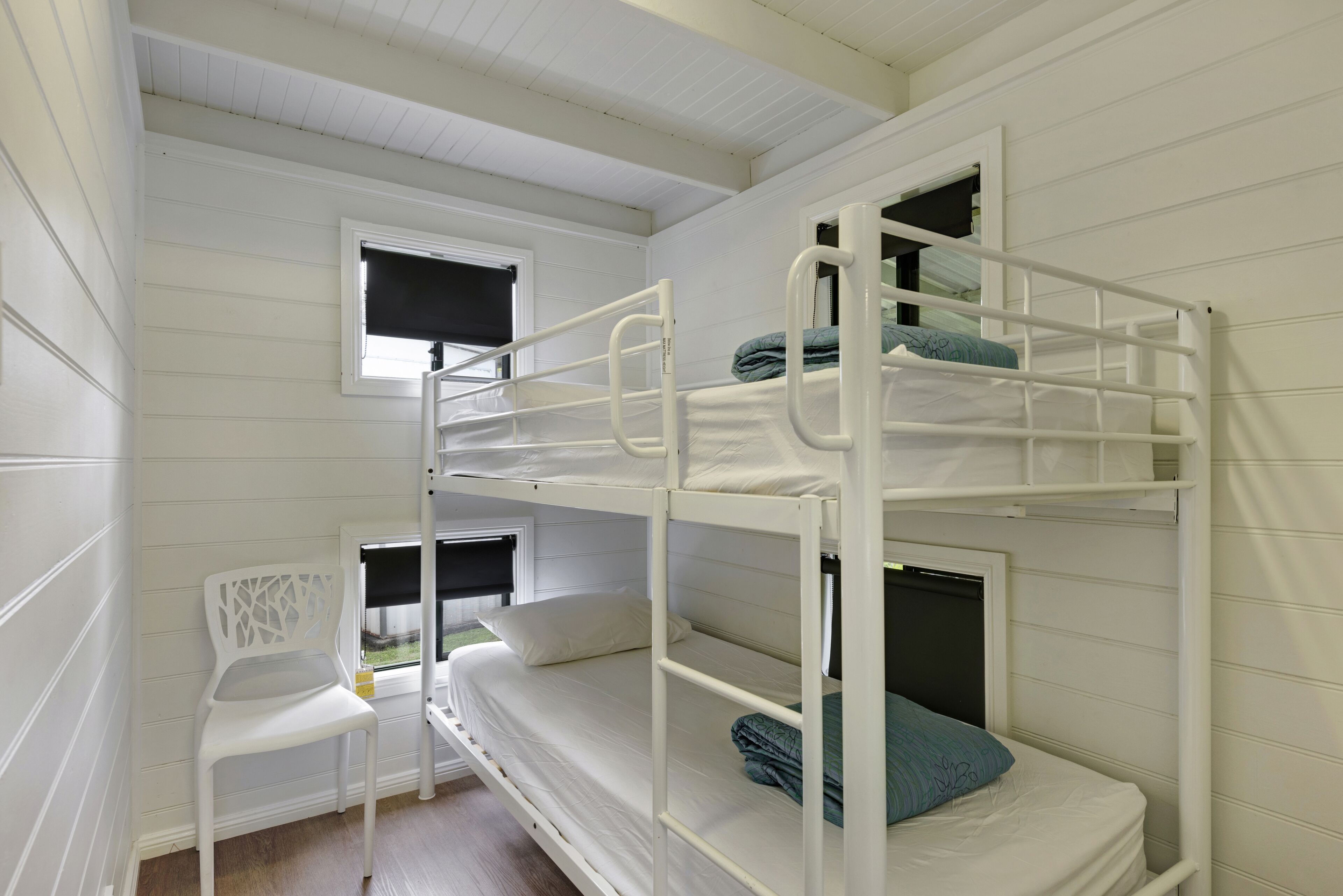 Habitación con literas, paredes blancas y una ventana.