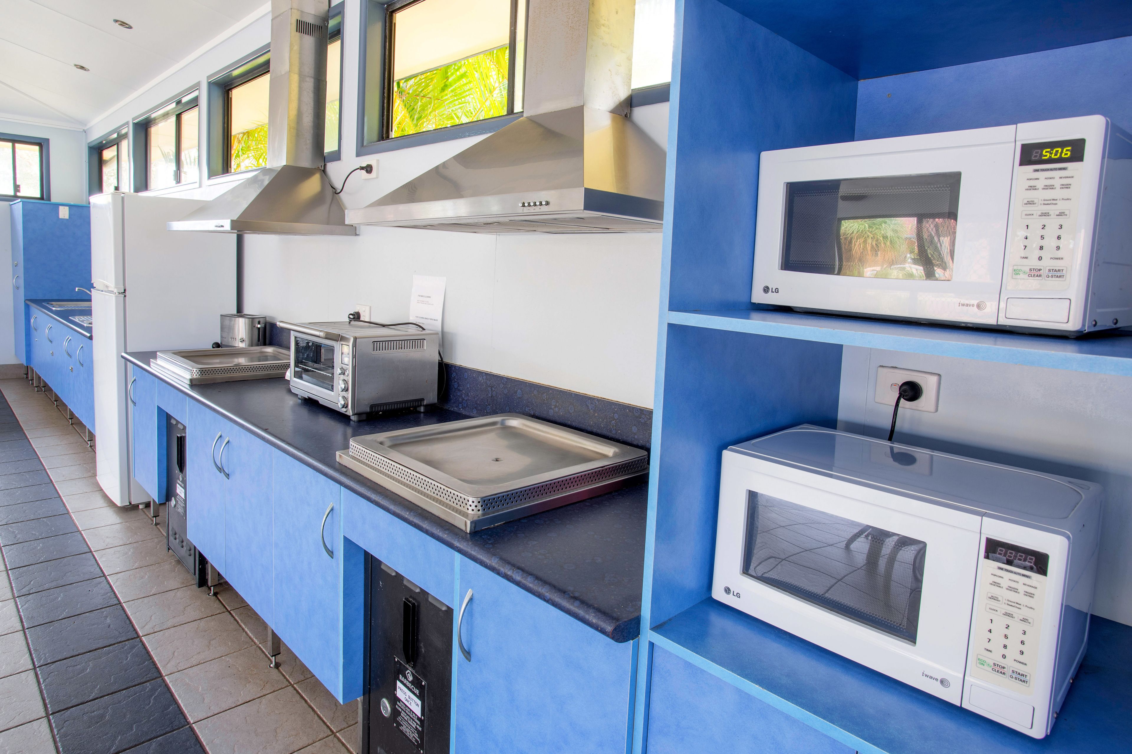 A kitchen with blue cabinets, a microwave, a toaster, and a stove.