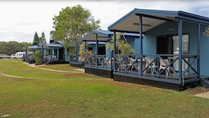 A row of blue mobile homes with balconies, each featuring a small outdoor seating area. - Discovery Parks - Ballina (East Ballina)
