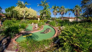 A golf course with a putting green, surrounded by lush greenery and palm trees. - Discovery Parks - Ballina (East Ballina)