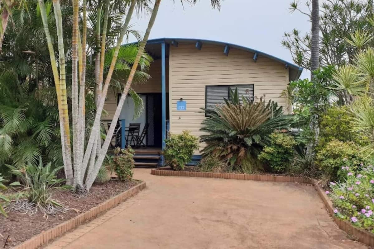 A single-story building with a curved roof, surrounded by tropical vegetation.