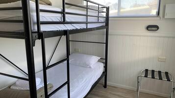 A bunk bed room with a window, a radiator, and a small table.