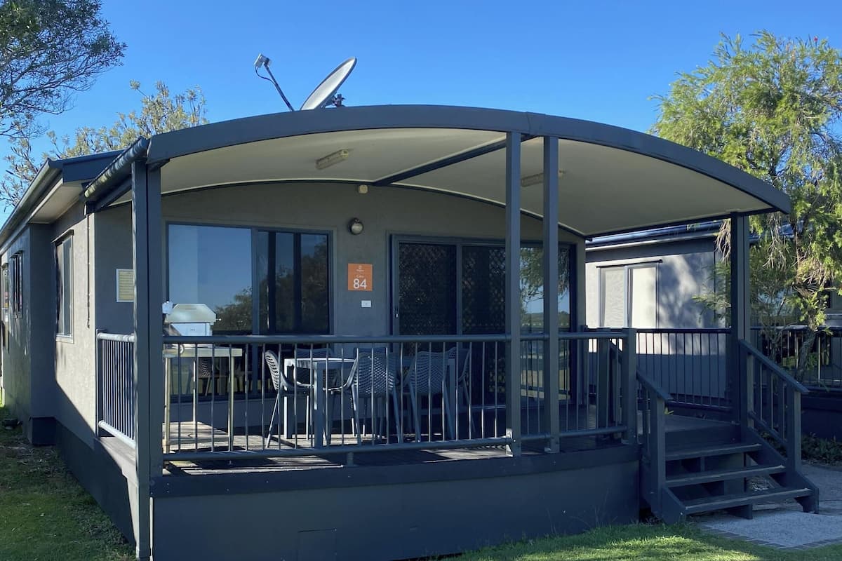A covered outdoor area with a patio, chairs, and a staircase.