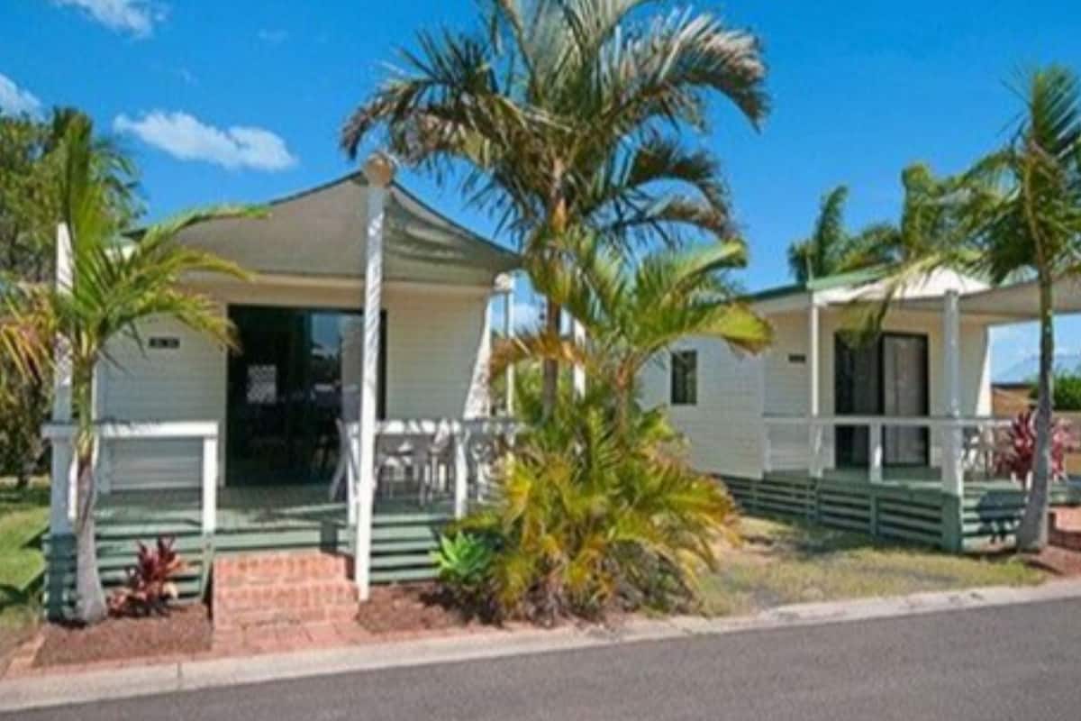 A single-story building with a porch, surrounded by palm trees.